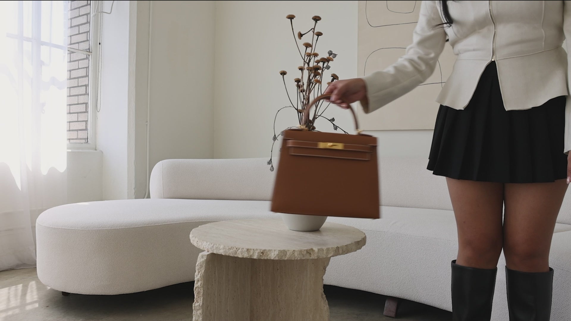 A well-dressed women placing luxury handbags for Luxury Bag Consignment & Resale on a stylish stone table