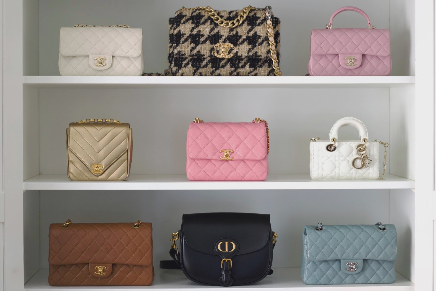 Luxxedition's used luxury handbag assortment displayed on white shelves